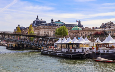 Fototapeta premium Pedestrian bridge (Passerelle Léopold-Sédar-Senghor) over Seine river, boats and historic buildings of Paris France
