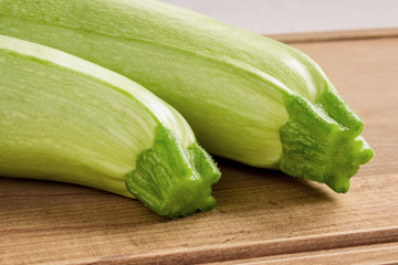 Two fresh green courgettes on a brown wooden cutting board. Cook at home. Fresh farm vegetables and healthy vegetarian food.