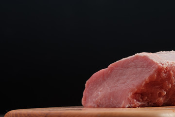 Raw pork tenderloin on a wooden cutting board on a dark background