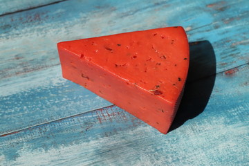 Red pesto cheese on a blue table in the rays of sunlight. Close-up.