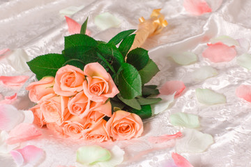 Very beautiful soft delicate pink roses with petals lie on the bed, romantic bouquet of pink roses on white sheets, romantic concept.