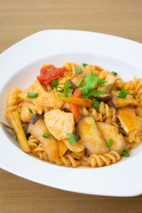 Pasta in sour and spicy sauce with Pleurotus Eryngii in white dish on wooden table.