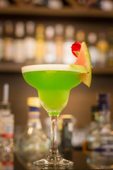 Green alcoholic cocktail with mint in a margarita glass on a bar counter