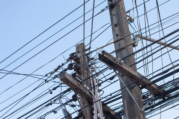 Closeup Electric pole with wires and communication cables with clear blue sky background.