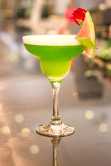 Green alcoholic cocktail with mint in a margarita glass on a bar counter