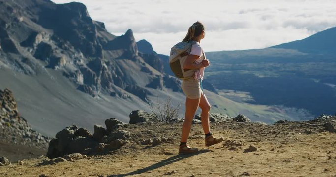 Young adventurous woman hiking in slow motion on the top of a mountain with view, amazing summer outdoors adventure