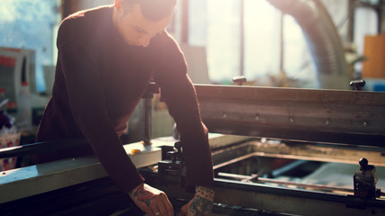 Man controls wide industrial printer in workshop