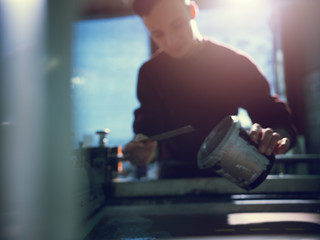 Man pouring container with silver color in workshop