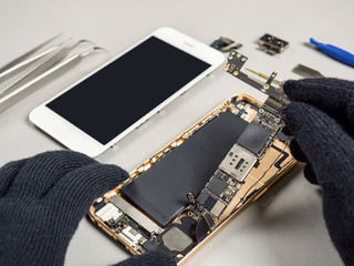 Technician or engineer disassembling components broken smartphone and take off logic board for...