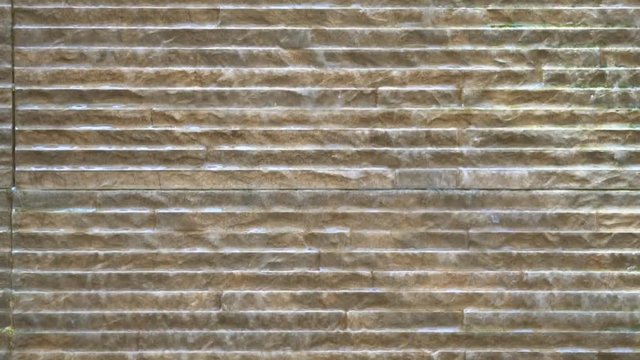 brown granite or marble wall with waterfall and water flow from interior or exterior architecture construction and texture background for fortune or feng shui at home or hotel on slow