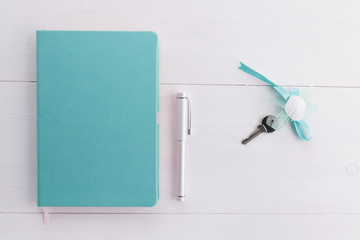mint color notebook with home keys and a pen concept of planing a house buying, mortgage, debt or property loan or gift