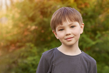 Portrait of kid boy in summer in the garden with the sun in the morning or at sunset. Flare