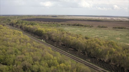 Fototapeta na wymiar A railway track passing through the forest and field. Shooting from a height. Russian railway, taken from a height.