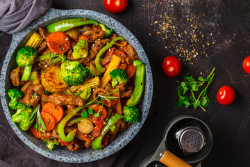 Fried beef stroganoff with potatoes and vegetables in a pan, top view.