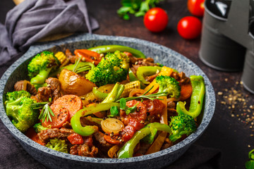 Fried beef stroganoff with potatoes and vegetables in a pan.