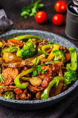 Fried beef stroganoff with potatoes and vegetables in a pan.