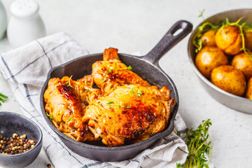 Grilled chicken and baked potatoes in a cast iron skillet.