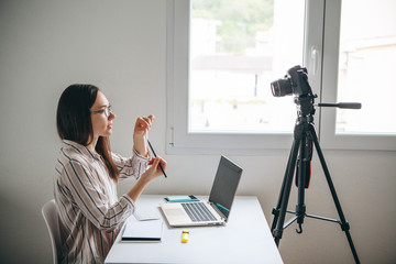 Girl video blogger or online foreign language teacher writes a training video for their subscribers...