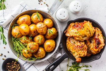 Grilled chicken and baked potatoes in a cast iron skillet.