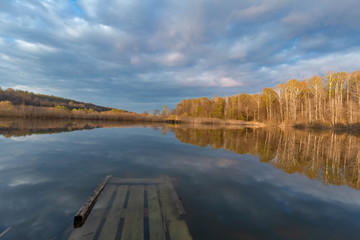 forest pond with reflections of clouds shot in the spring at sunset