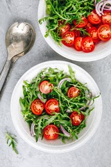 Healthy Green Fresh Arugula Salad Bowl with Tomatoes and Red Onions. Top view