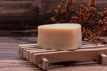 Wooden Soap Holder with a Heart shaped Goat milk Soap on wooden background.