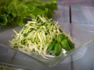 Fresh cabbage and cucumber salad on a glass plate, with dill and balisik on a board tray