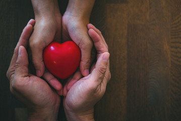Love concepts, heart in hands,adult and child hands holding red heart with cardiogram, health care,...