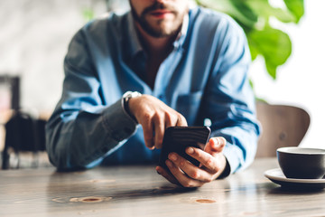 Handsome bearded hipster man use smartphone with coffee at table in cafe.Communication and technology concept