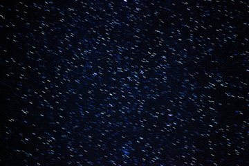 Stars motion on a long exposition at the night shining starry sky, black space background with...
