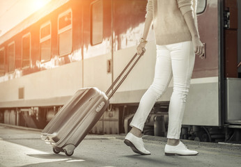 Woman with her luggage go near the red train on the peron os rai