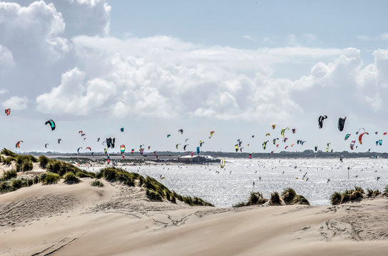 Coastline at Brouwersdam, Zeeland, the Nethrlands, with sandy dunes and hundereds of colorful kites under a cloudy sky