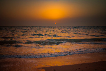 Fototapeta na wymiar Nature background of amazing beach sunset with endless horizon and incredible foamy waves. It is Atlantic ocean in tropical paradise in Senegal, Africa. There is beautiful golden sun.
