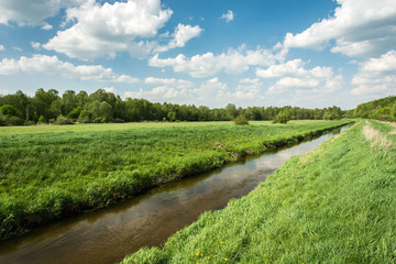 Fototapeta na wymiar Eastern Poland and river flowing through meadow, forest and clouds on blue sky