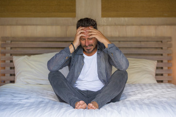 young attractive overwhelmed and depressed man sitting on bed crying sad and frustrated suffering depression crisis feeling desperate and helpless in bedroom