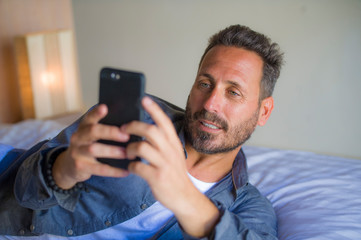 young handsome and happy man at home using internet mobile phone on bed smiling cheerful and satisfied feeling relaxed dating online or enjoying social media app
