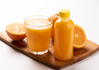 Orange juice in bottle with slices of orange on wooden board over white background