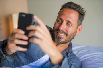 young handsome and happy man at home using internet mobile phone on bed smiling cheerful and satisfied feeling relaxed dating online or enjoying social media app