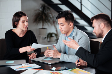 Making great decisions. Young beautiful man woman discussing something with smile while her coworkers listening to her sitting at the office table, group team young freelancers