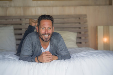 Fototapeta premium interior portrait of 30s to 40s happy and handsome man at home in casual shirt and jeans lying on bed relaxed at home smiling confident and happy feeling positive