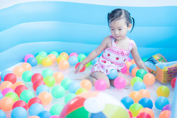 Fototapeta na wymiar little children enjoy and have fun playing water in inflatable pool with colorful of small balls