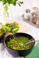 Fresh hot vegetable soup in a black plate on the table