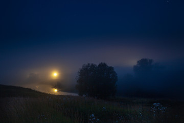 Fog over the night river in the village under the blue night sky