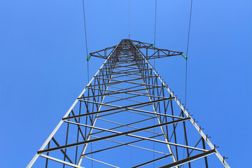 Metal pylon of the power line. Close-up. Isolated object against the blue sky. Bottom-up view. Background. Texture.