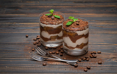 two portions Classic tiramisu dessert in a glass on wooden background