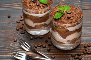 two portions Classic tiramisu dessert in a glass on wooden background