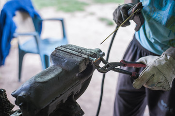 Worker with protective gloves welding metal part in workshop