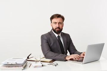 Portrait of an outraged office top manager who was distracted from work, sitting at desktop in...