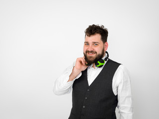 cool man with black beard and white shirt is posing with headphones and smartphone in front of white background