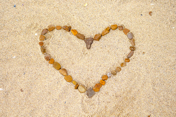 Fototapeta na wymiar heart laid out of stones on the sandy shore of the sea or ocean